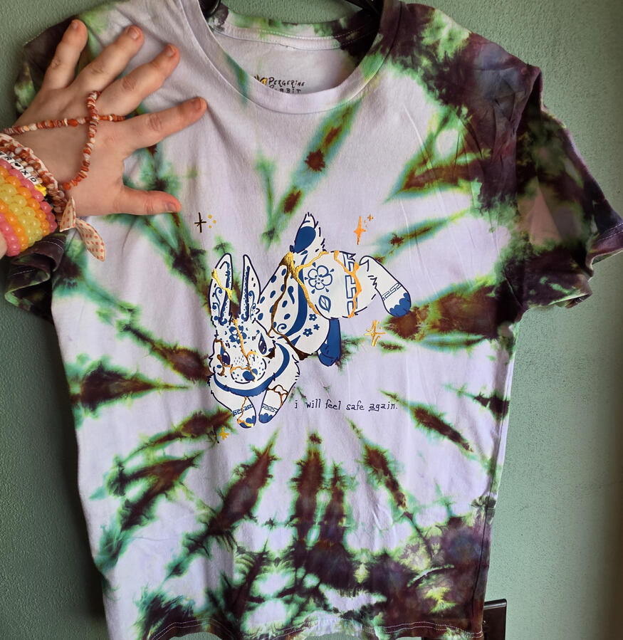 "KINTSUGI" Tee, an example in size medium; shirt ice tie-dyed in house, DTF transfer designed in-house and then shipped in and pressed, followed by a layer of metalic foil vinyl, cut and applied in-house.